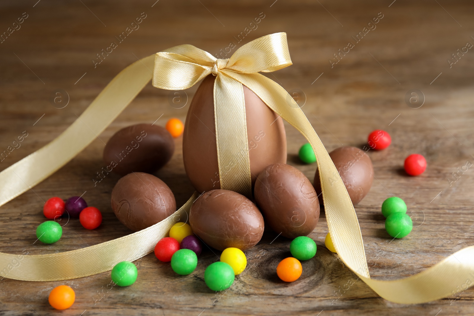 Photo of Tasty chocolate eggs and colorful candies on wooden table