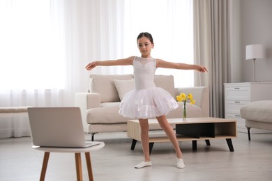 Photo of Cute little girl taking online dance class at home