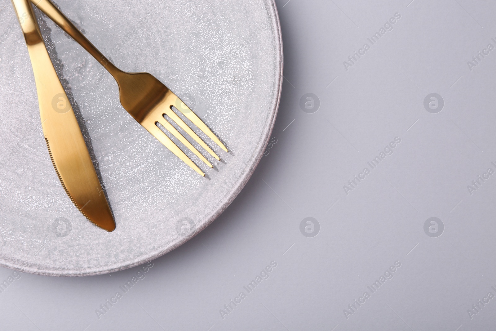 Photo of Setting with stylish cutlery on grey table, top view. Space for text