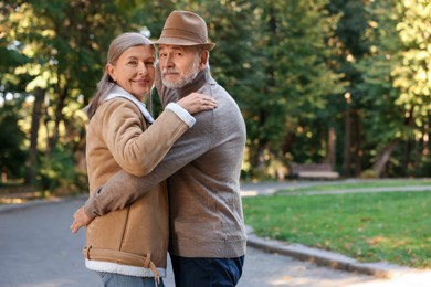Photo of Affectionate senior couple dancing together in park, space for text