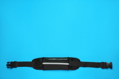 Photo of Stylish black waist bag on light blue background, top view. Space for text