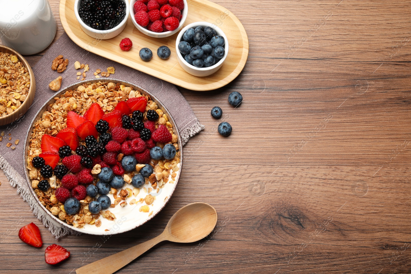 Photo of Healthy muesli served with berries on wooden table, flat lay. Space for text