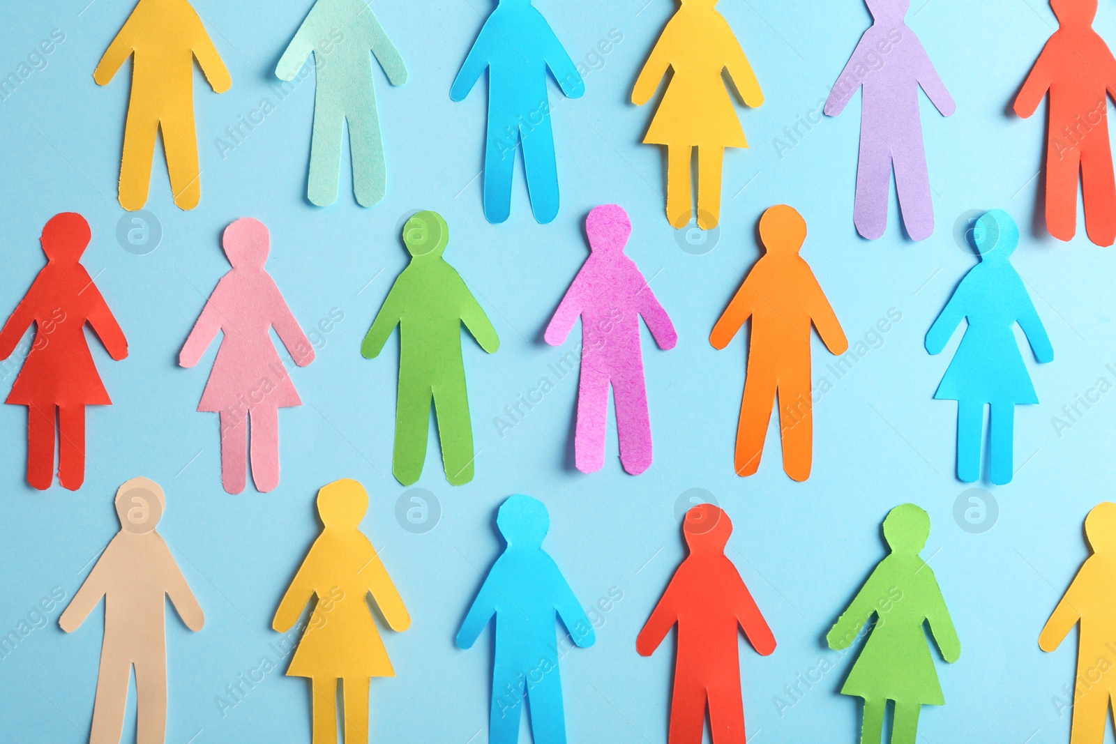 Photo of Many different paper human figures on light blue background, flat lay. Diversity and inclusion concept