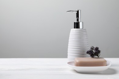 Soap bar and bottle dispenser on wooden table against white background, space for text