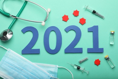 Photo of Flat lay composition with coronavirus vaccine and number 2021 on turquoise background