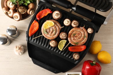 Photo of Flat lay composition with electric grill and homemade sausages on wooden table