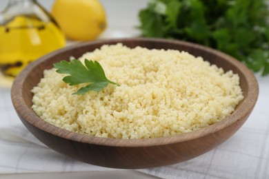 Photo of Tasty couscous with parsley on white table, closeup