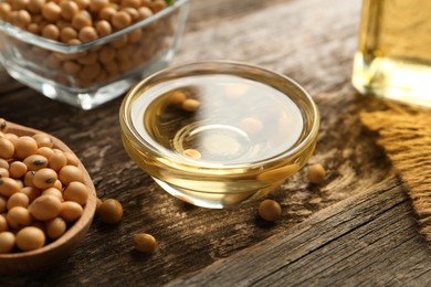 Photo of Soybeans and bowl of oil on wooden table, closeup