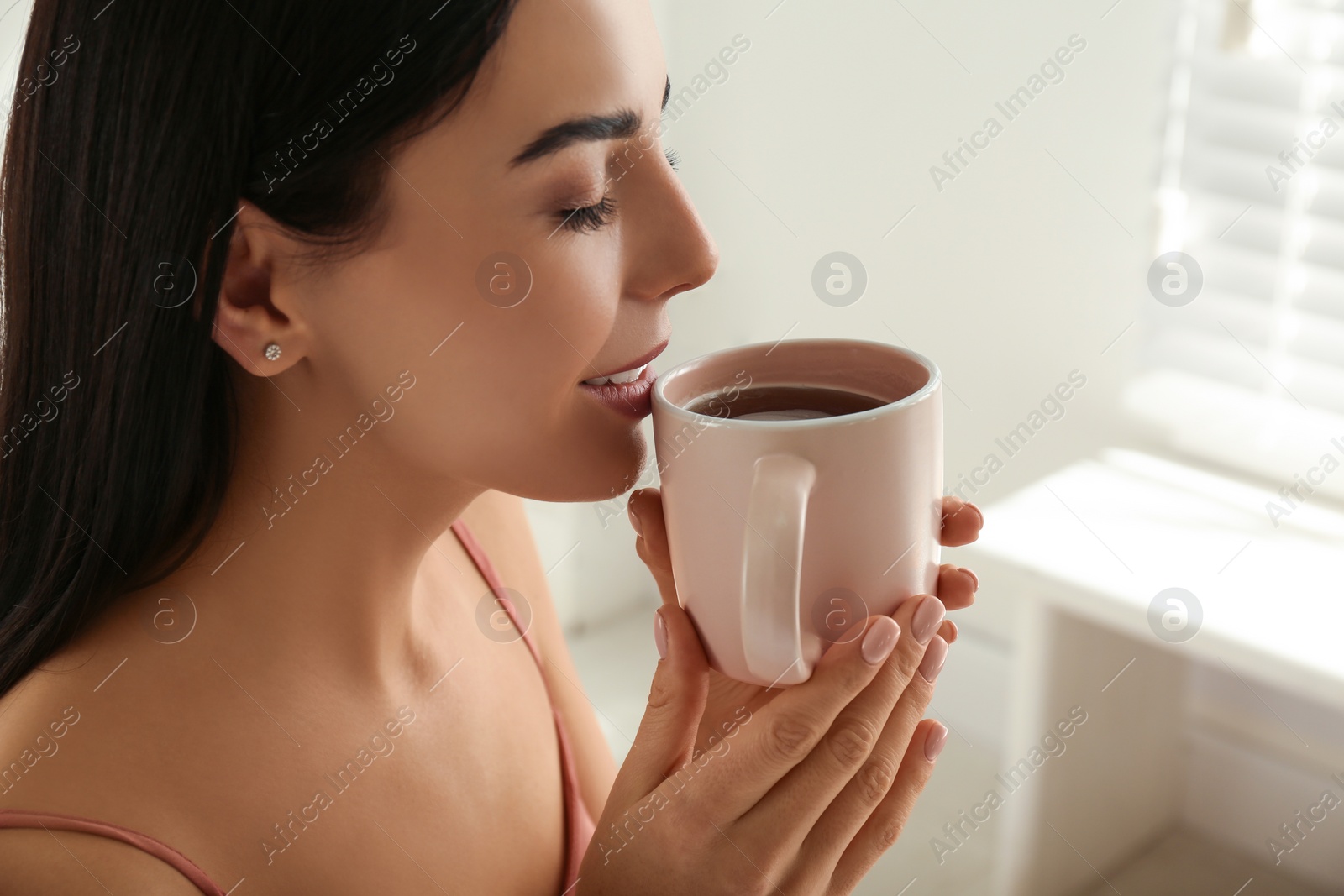 Photo of Woman with cup of tea in bedroom. Lazy morning