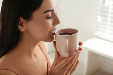 Woman with cup of tea in bedroom. Lazy morning