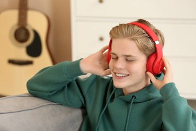 Teenage boy listening to music with headphones in room