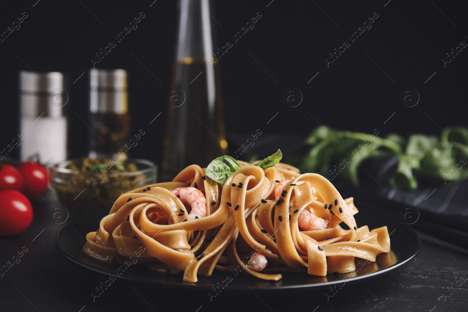 Image of Tasty buckwheat noodles with shrimps served on black table. Food photography  