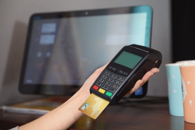 Photo of Woman using credit card machine for non cash payment in cafe, closeup. Space for text