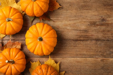 Photo of Fresh ripe pumpkins and dry leaves on wooden table, flat lay. Space for text