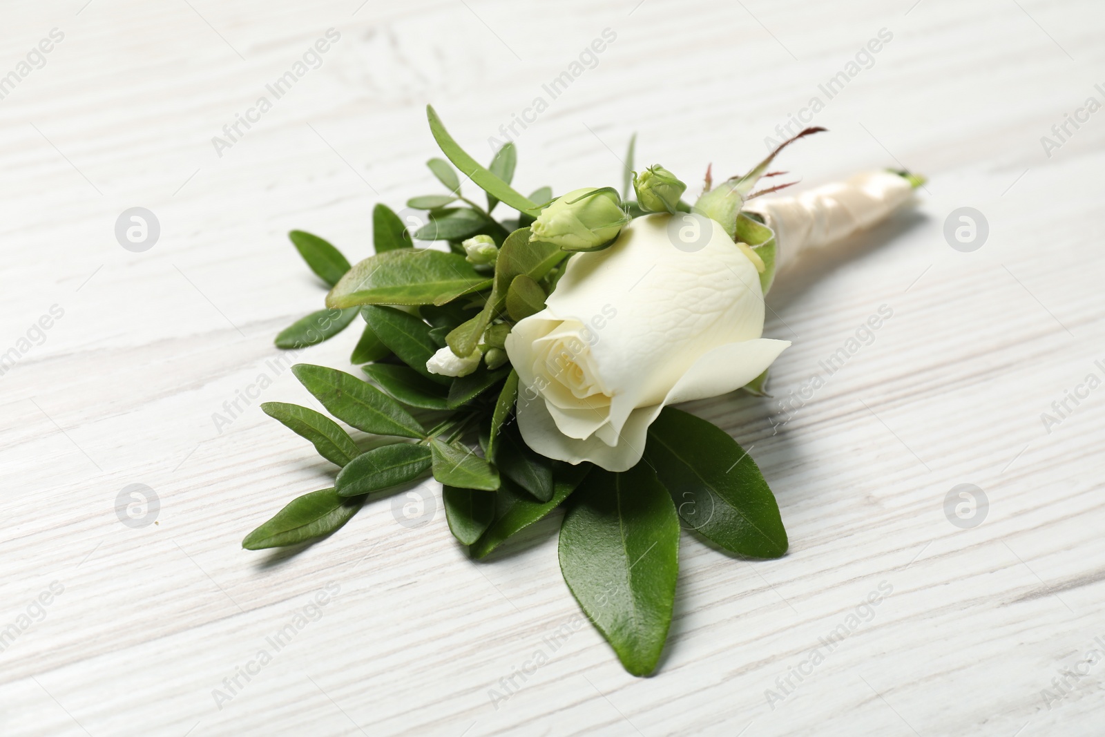 Photo of Wedding stuff. Stylish boutonniere on white wooden table, closeup