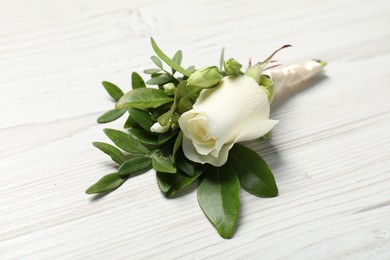 Photo of Wedding stuff. Stylish boutonniere on white wooden table, closeup