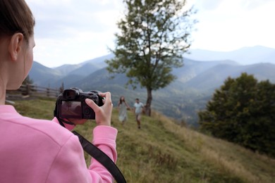 Photo of Professional photographer taking picture of couple in mountains, closeup