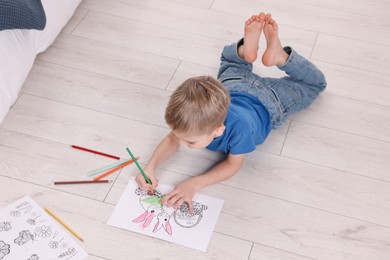 Photo of Little boy coloring on warm floor at home. Heating system