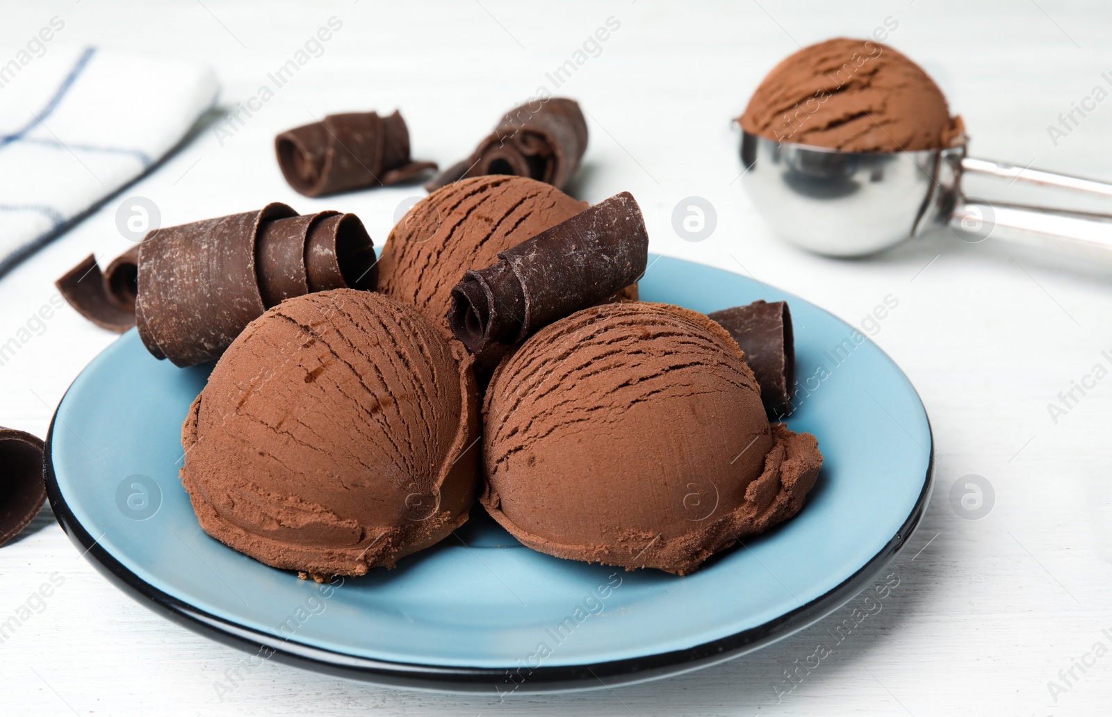 Photo of Plate of ice cream and chocolate curls on white wooden table