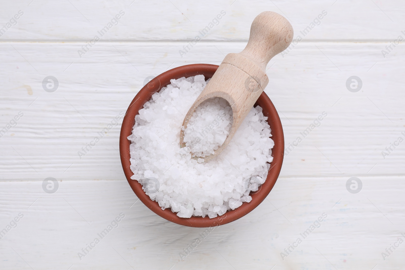 Photo of Bowl and scoop with sea salt on white wooden table, top view