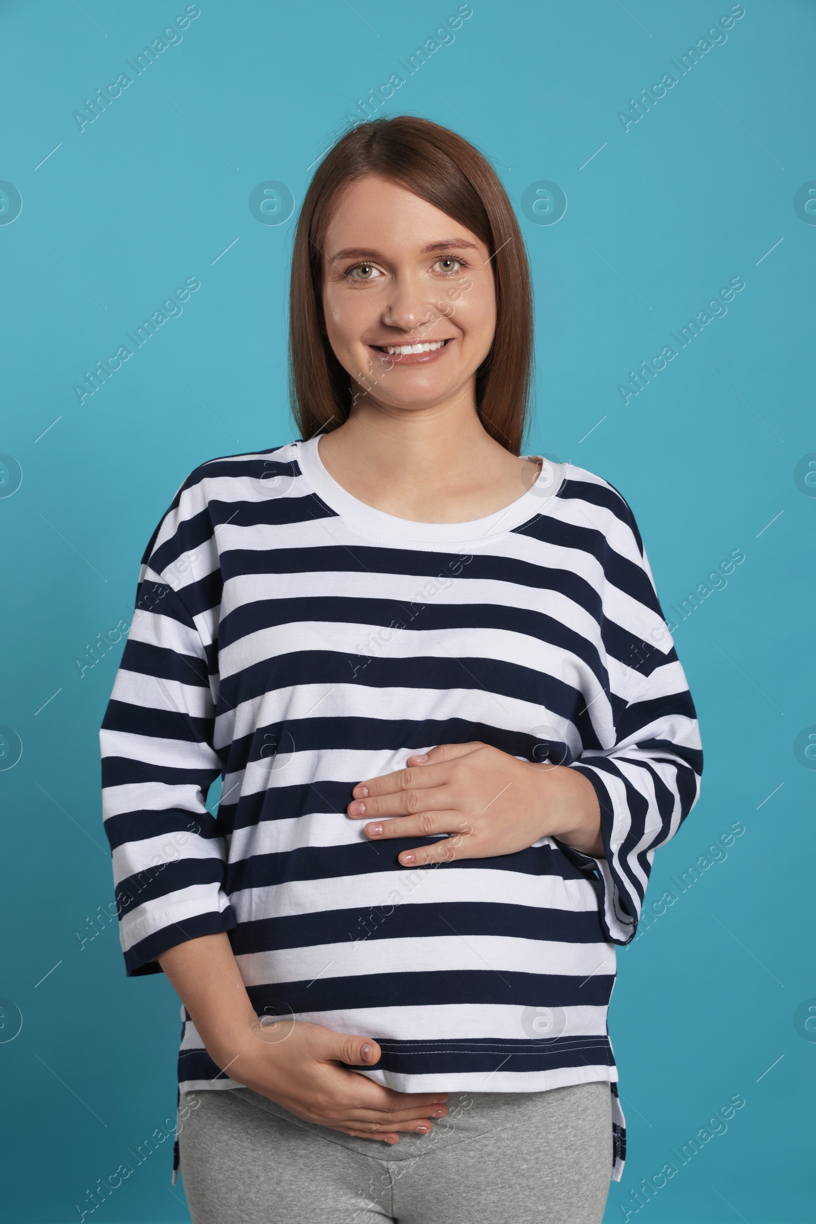 Photo of Happy young pregnant woman on light blue background