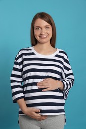 Photo of Happy young pregnant woman on light blue background