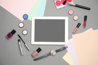 Flat lay composition with tablet and makeup products for woman on grey background