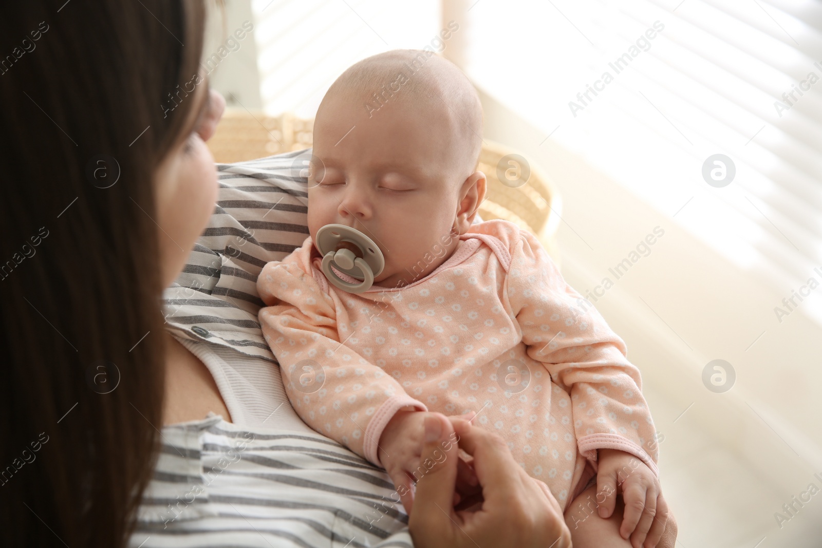 Photo of Mother holding her sleeping baby near window, closeup