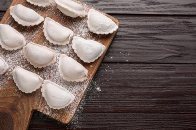 Photo of Raw dumplings (varenyky) on brown wooden table, top view. Space for text