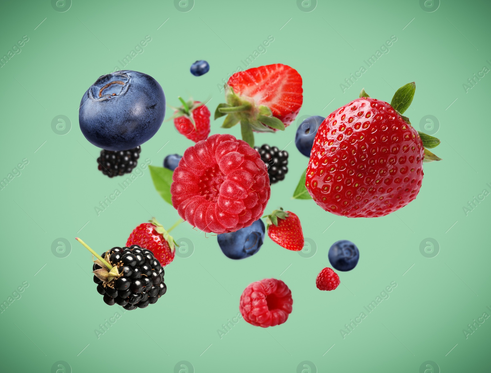 Image of Many different fresh berries falling on aquamarine color background