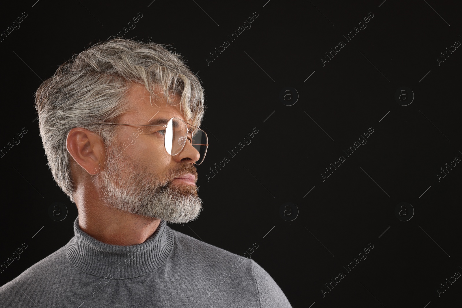 Photo of Portrait of confident man with beautiful hairstyle on black background. Space for text