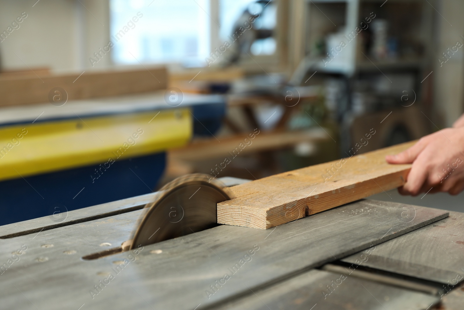 Photo of Working man using circular saw at carpentry shop, closeup