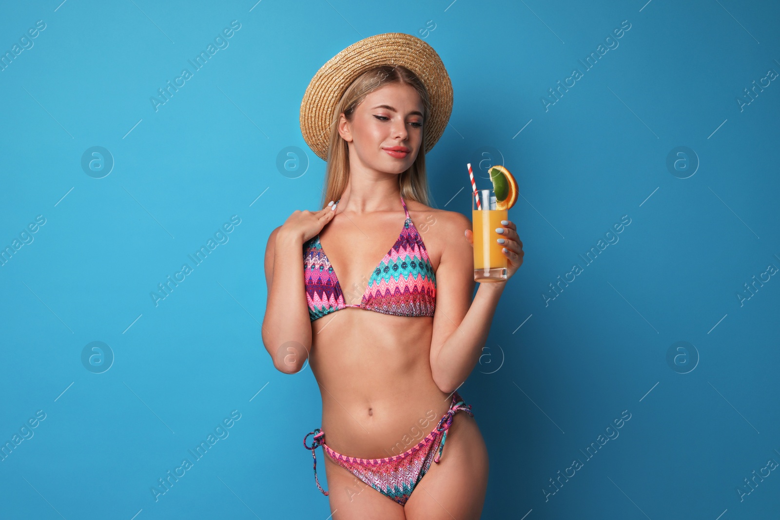 Photo of Pretty young woman wearing stylish bikini with cocktail on blue background