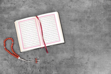 Photo of Muslim prayer beads, Quran and space for text on grey background, top view