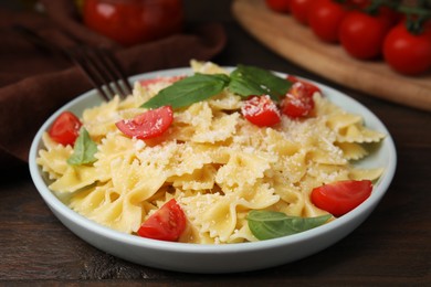 Photo of Tasty pasta with tomato, cheese and basil on wooden table, closeup