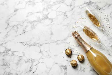 Flat lay composition with bottle of champagne for celebration on white marble background. Space for text