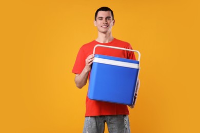 Man with blue cool box on orange background