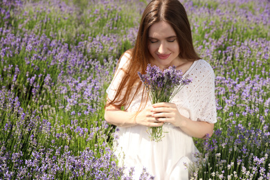 Young woman with lavender bouquet in field on summer day