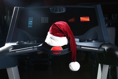 Photo of Santa hat on fitness treadmill in modern gym