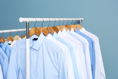 Photo of Racks with clean clothes after dry-cleaning against color background