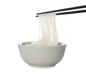 Photo of Chopsticks with cooked rice noodles over bowl isolated on white