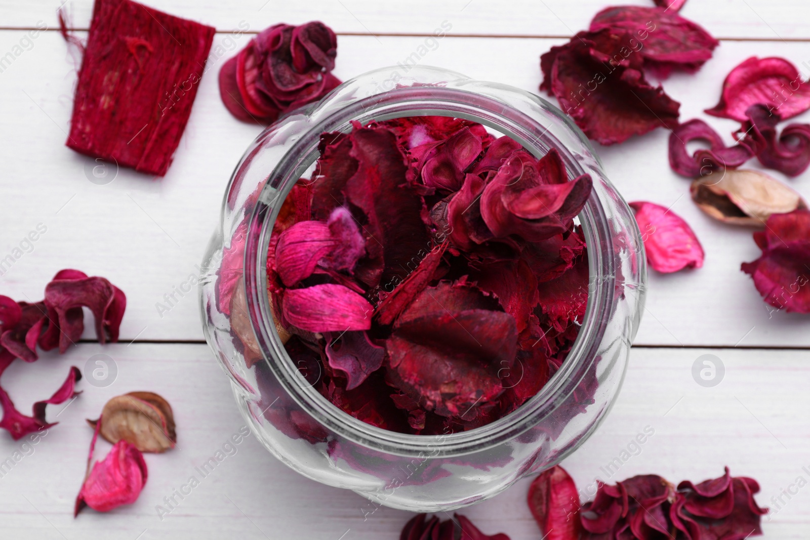 Photo of Aromatic potpourri of dried flowers in glass jar on white wooden table, flat lay