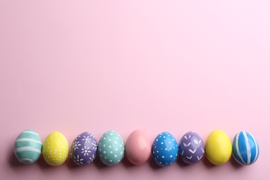 Flat lay composition of painted Easter eggs on color background, space for text