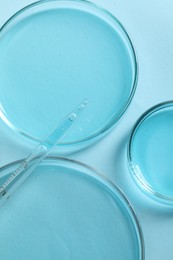 Photo of Measuring pipette and petri dishes on light blue table, flat lay