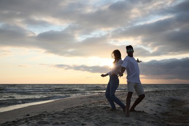 Photo of Happy couple dancing on beach at sunset