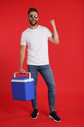 Photo of Happy man with cool box on red background
