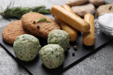 Falafel balls and different raw vegan meat products on dark board, closeup