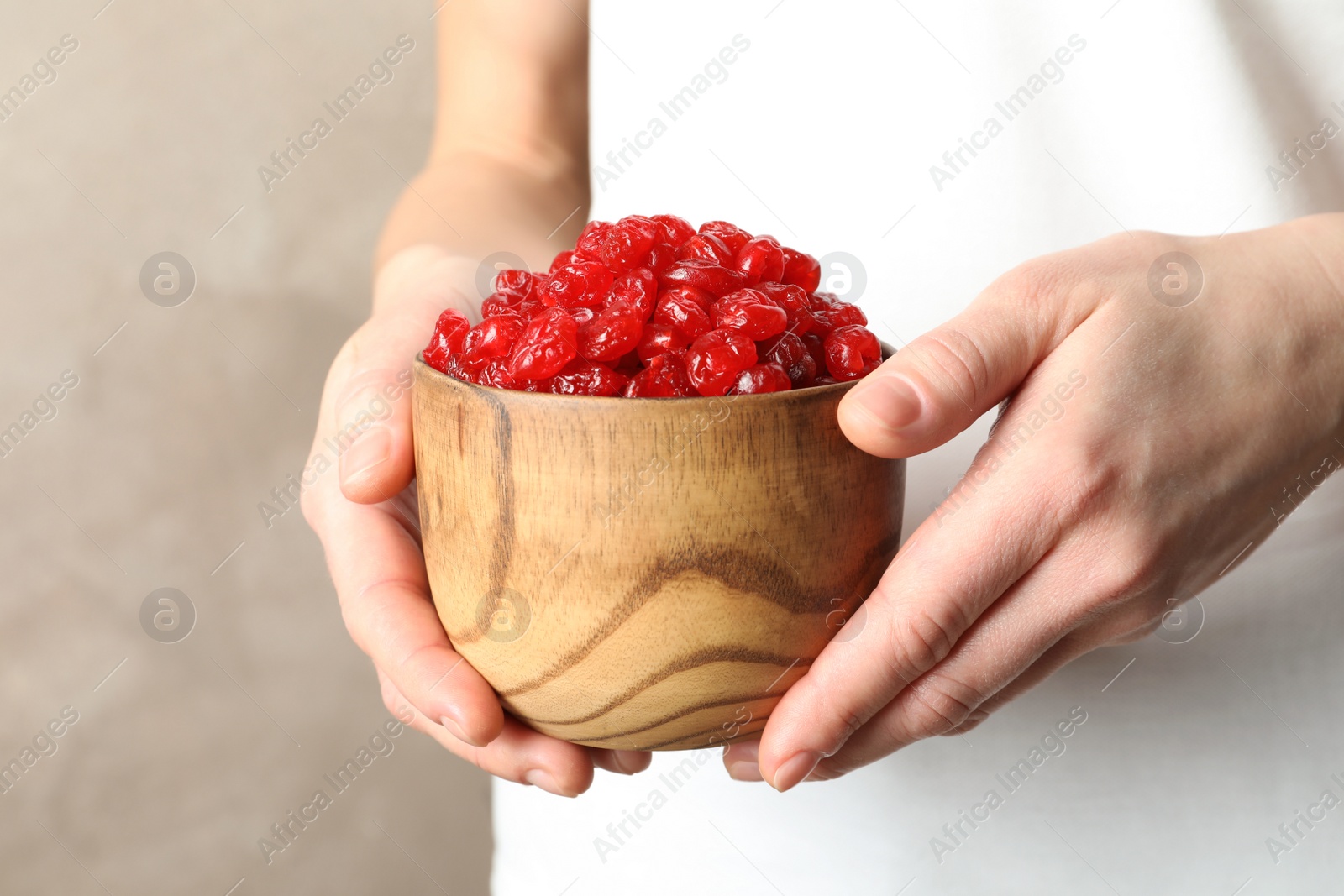 Photo of Woman holding bowl with tasty cherries on color background, closeup. Dried fruits as healthy food