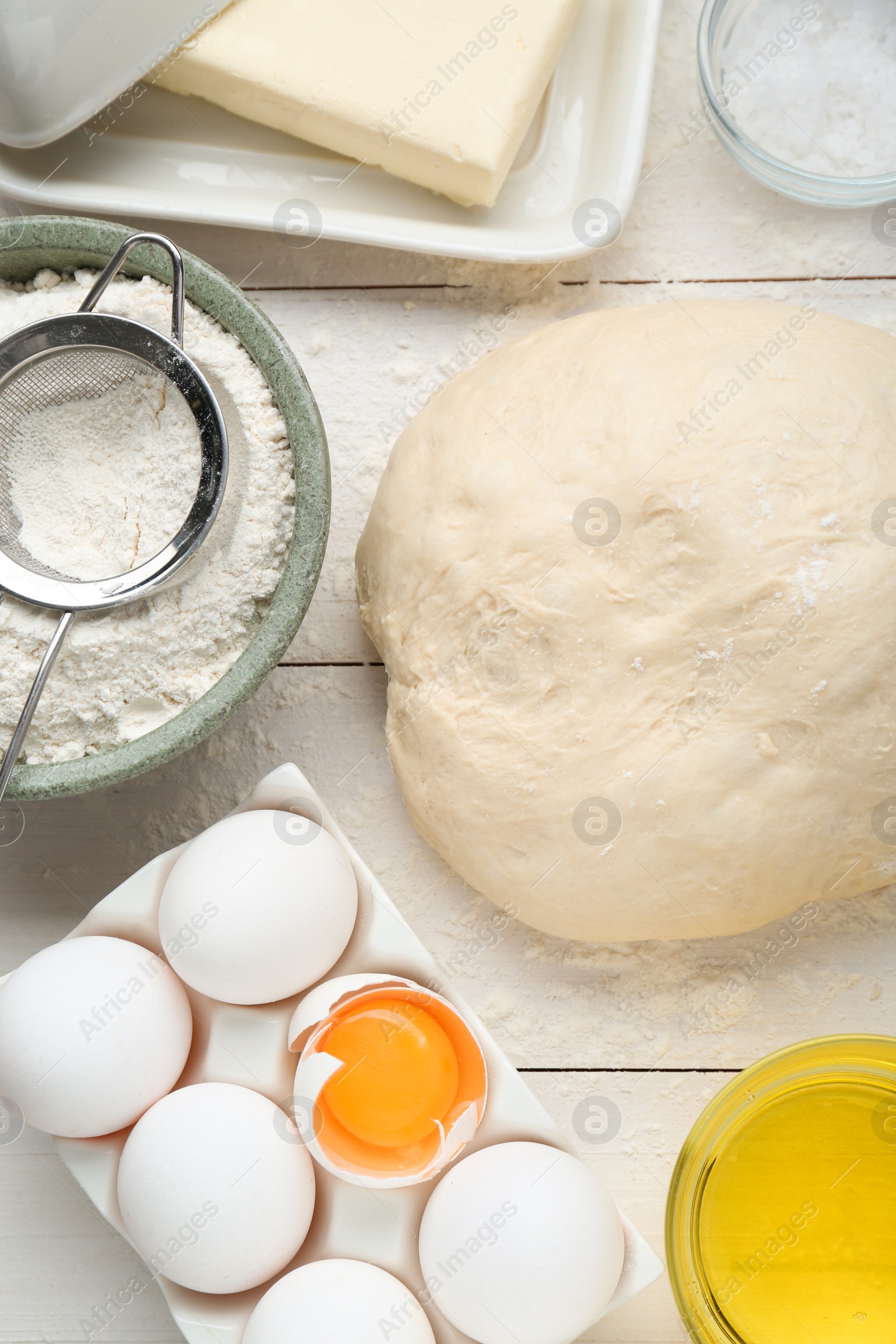 Photo of Fresh yeast dough and ingredients on white wooden table, flat lay