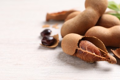 Delicious ripe tamarinds on white wooden table, closeup. Space for text